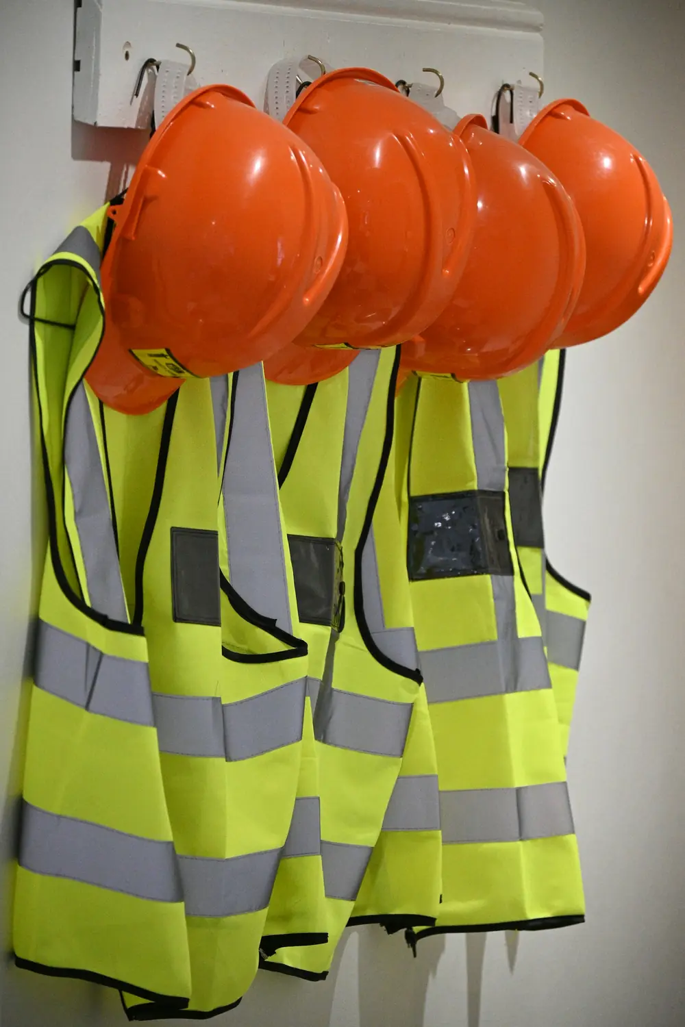 Casques orange et gilets haute visibilité suspendus